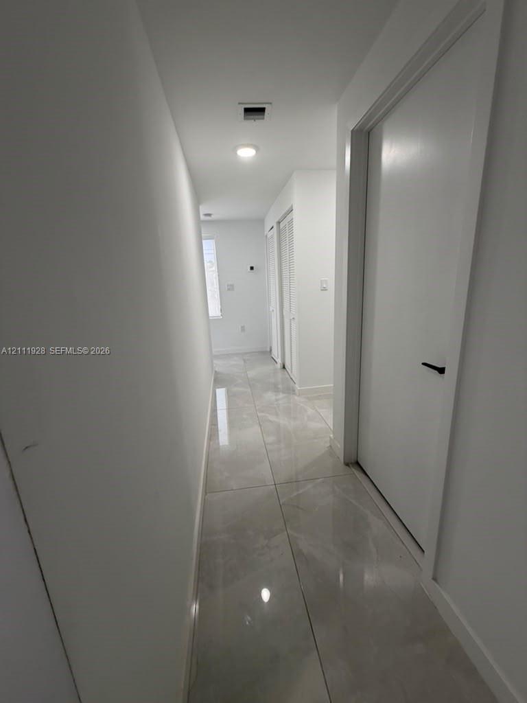 Hallway featuring large-format polished tile flooring, recessed lighting, and interior doors with matte black hardware