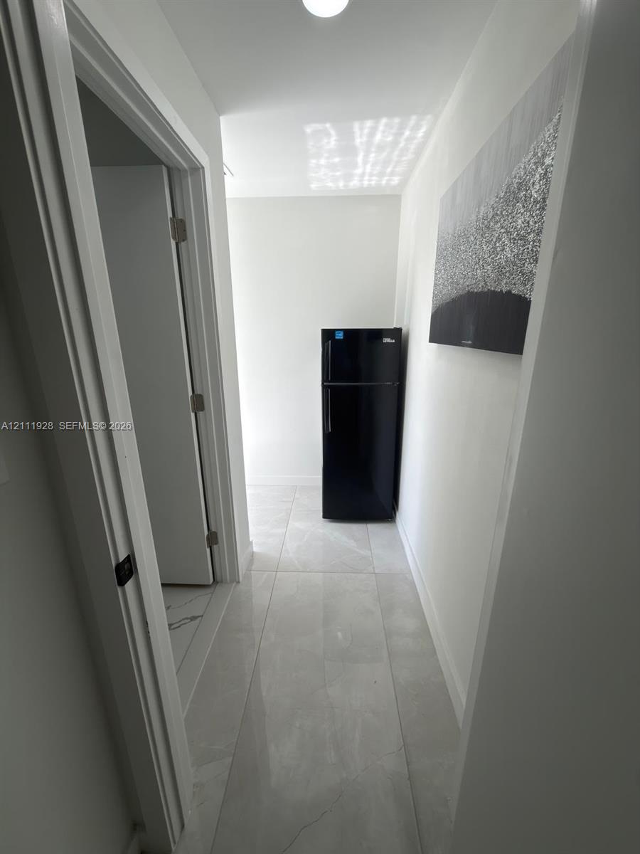 Large-format tile flooring, flush-mount ceiling lighting, and solid-core interior doors with matte black hardware