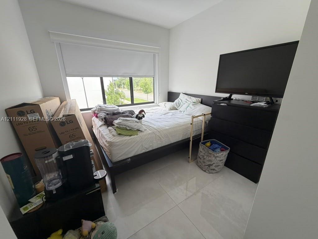 Large-format tile flooring, oversized window with integrated roller shade, and neutral wall finishes
