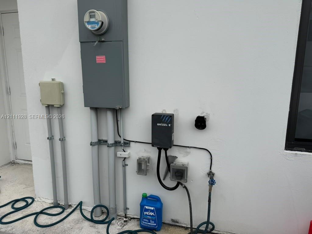 Exterior electrical panel with an integrated electric vehicle charging station and wall-mounted utility outlets