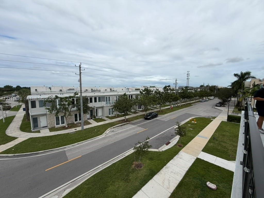 Exterior aerial perspective featuring multi-story residential structures with stone veneer accents, integrated balcony railings, concrete sidewalks, and landscaped grass buffers