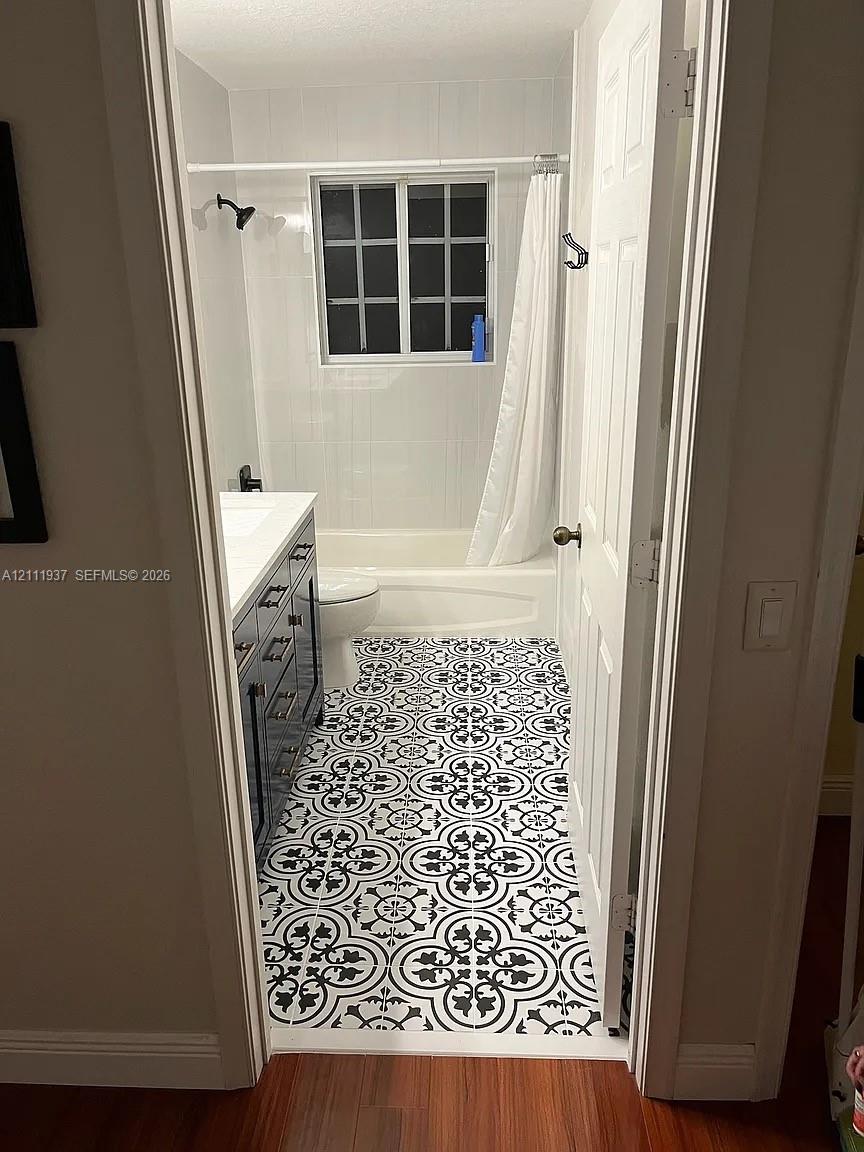 Bathroom featuring patterned tile flooring, a dark-toned vanity with a white countertop, and a shower-tub combination with white wall tile