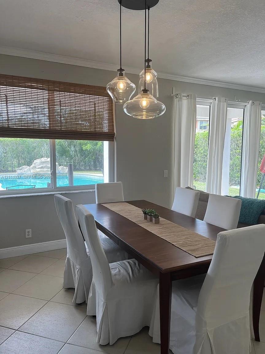 Multi-light pendant fixture with clear glass shades, tile flooring, large windows, and sliding glass doors