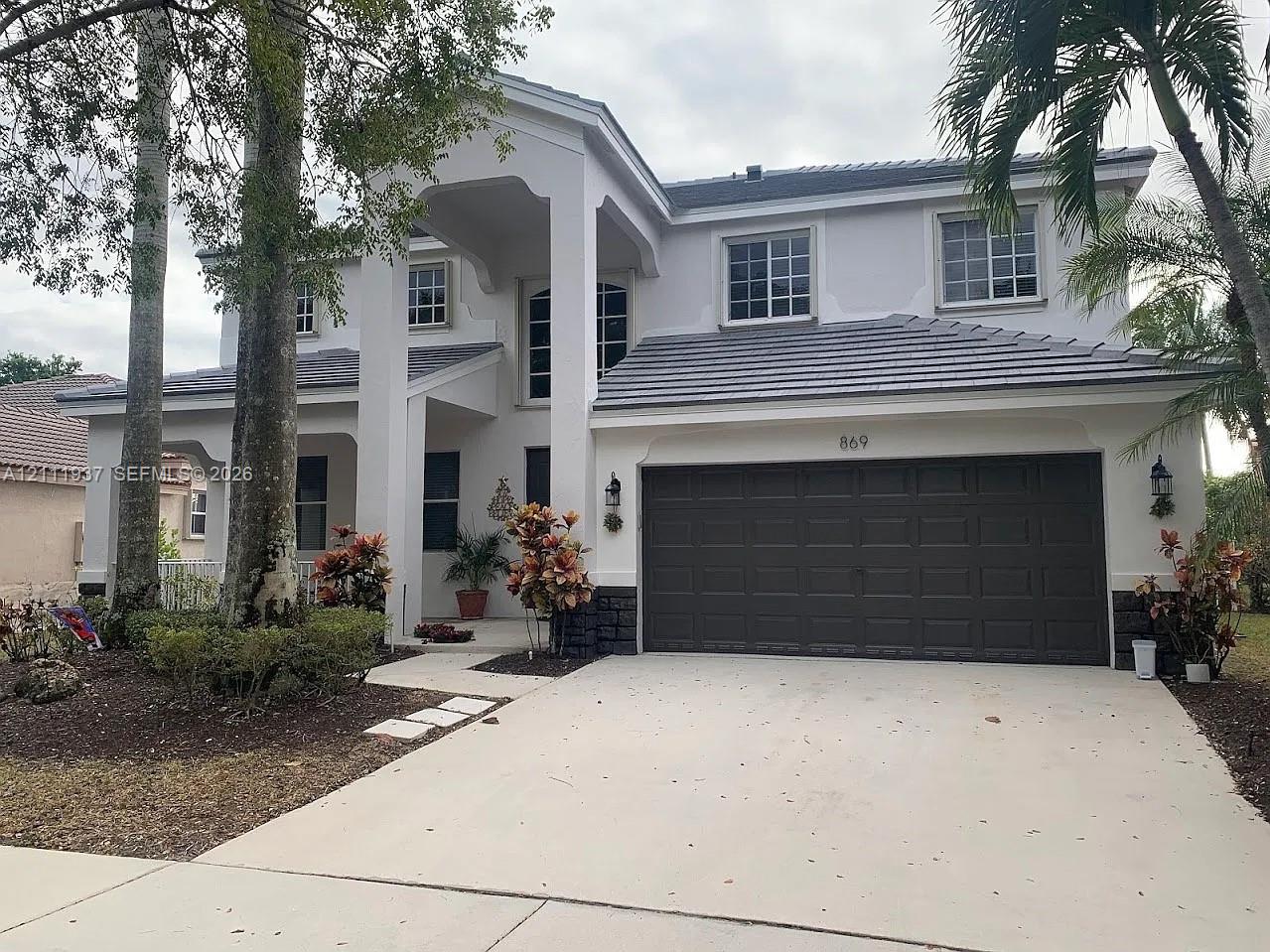 Two-story residence featuring a tile roof, stucco exterior, covered entryway, and a two-car garage