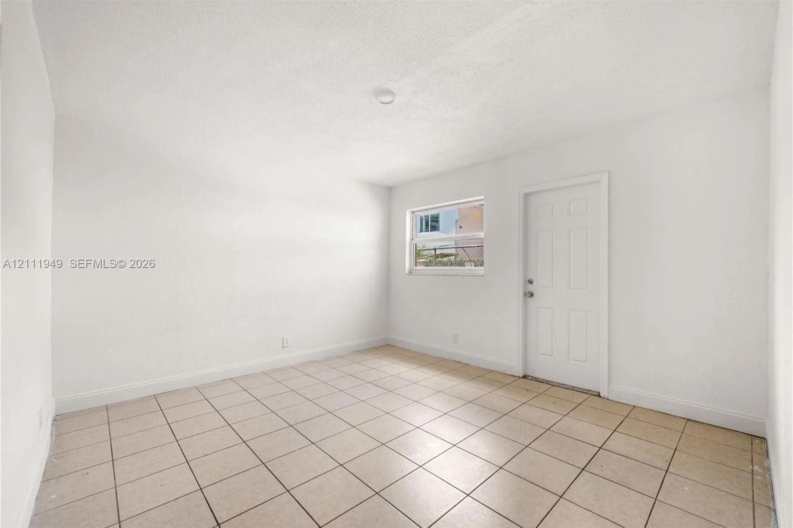Interior space featuring neutral wall finishes, large-format ceramic floor tile, and a six-panel exterior door
