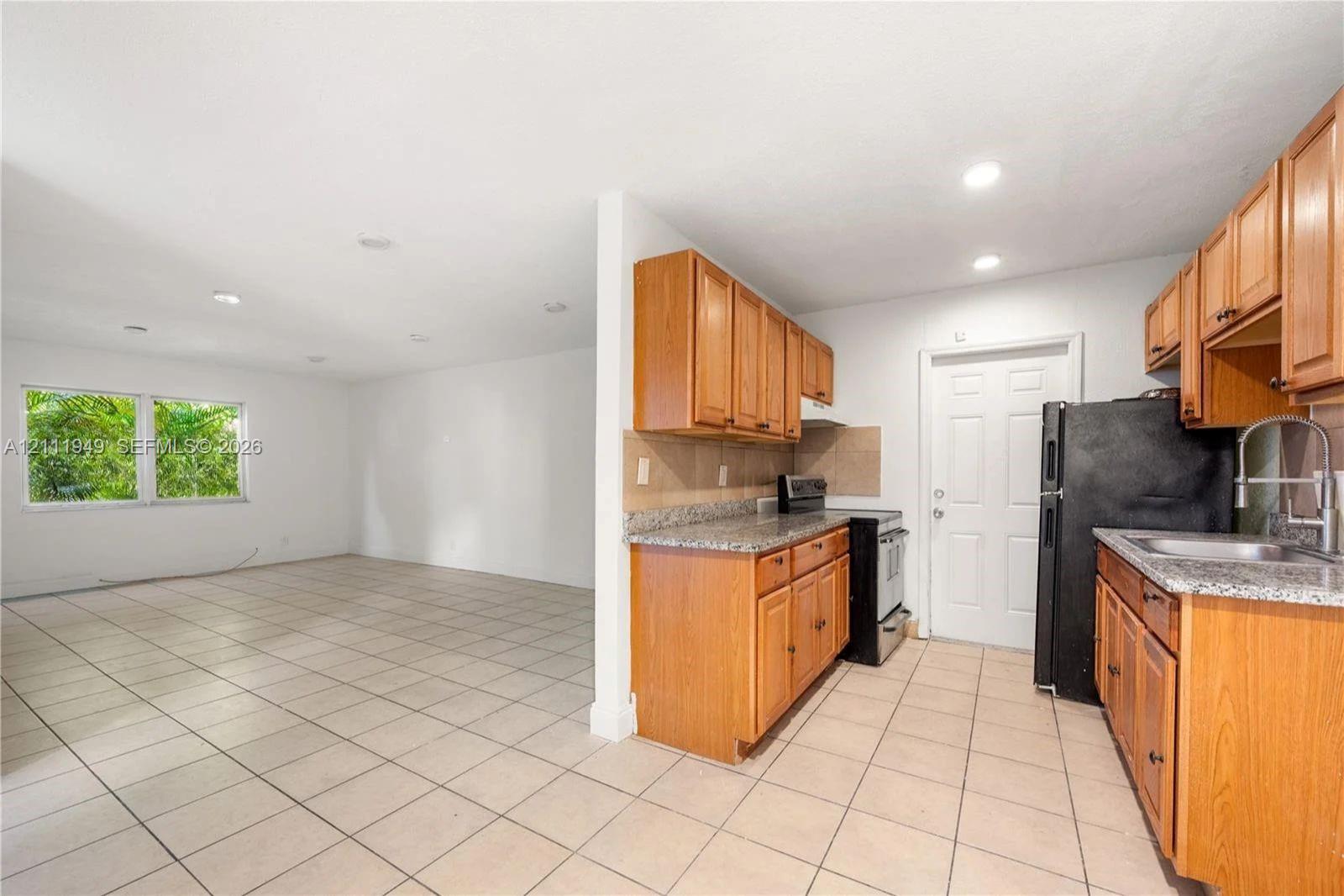 Kitchen featuring wood cabinetry, stone-finish countertops, recessed lighting, and tile flooring throughout