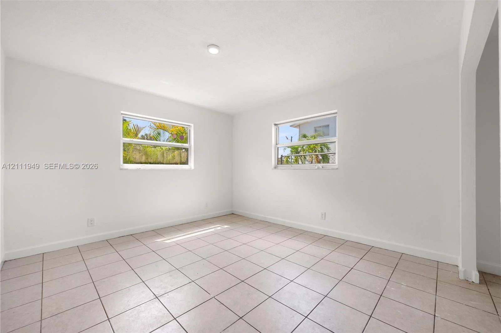 Interior room featuring neutral wall paint, tile flooring, and dual single-hung windows