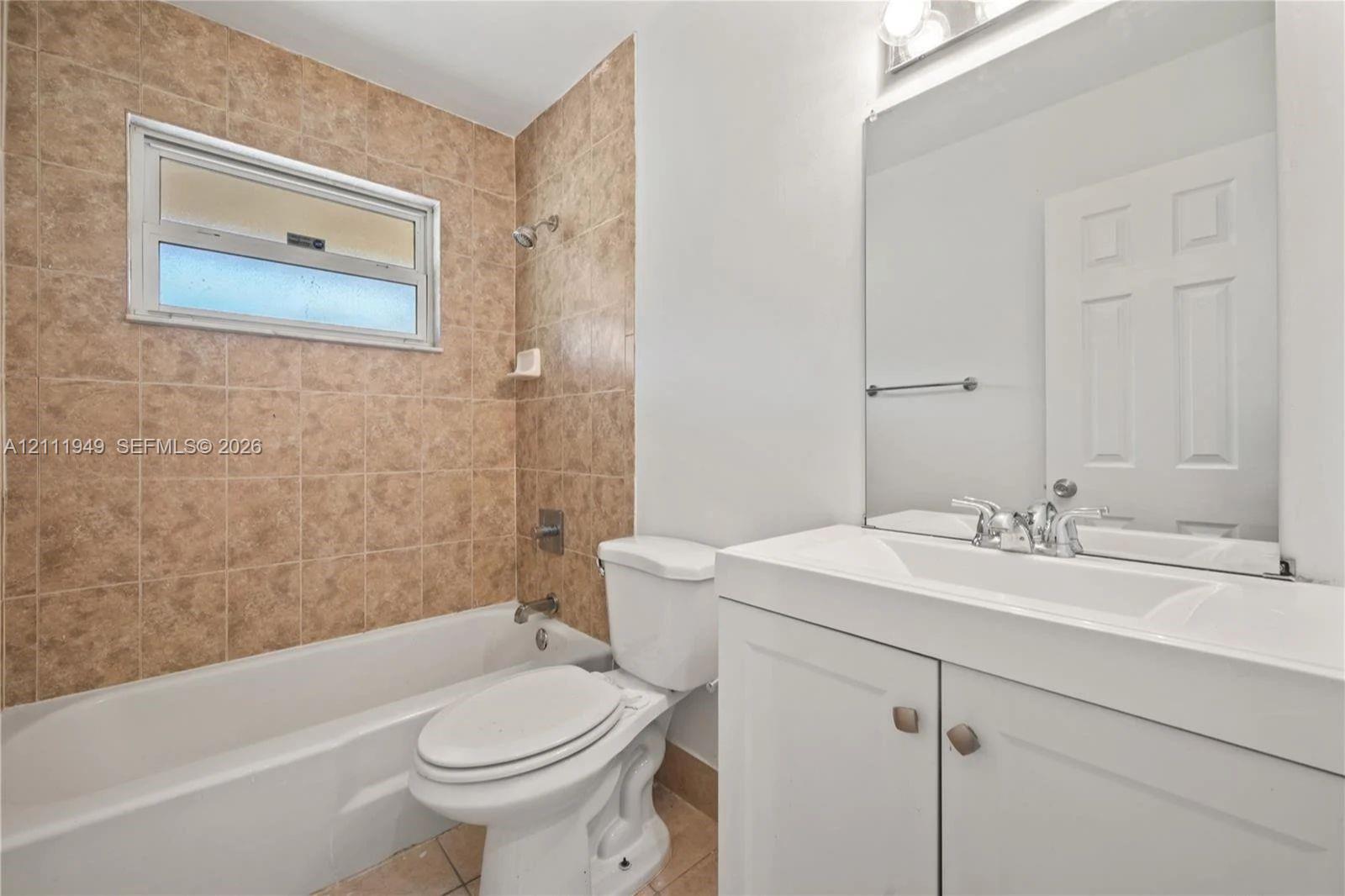Bathroom featuring a vanity with white cabinetry, a single-basin sink, and a full-width wall mirror