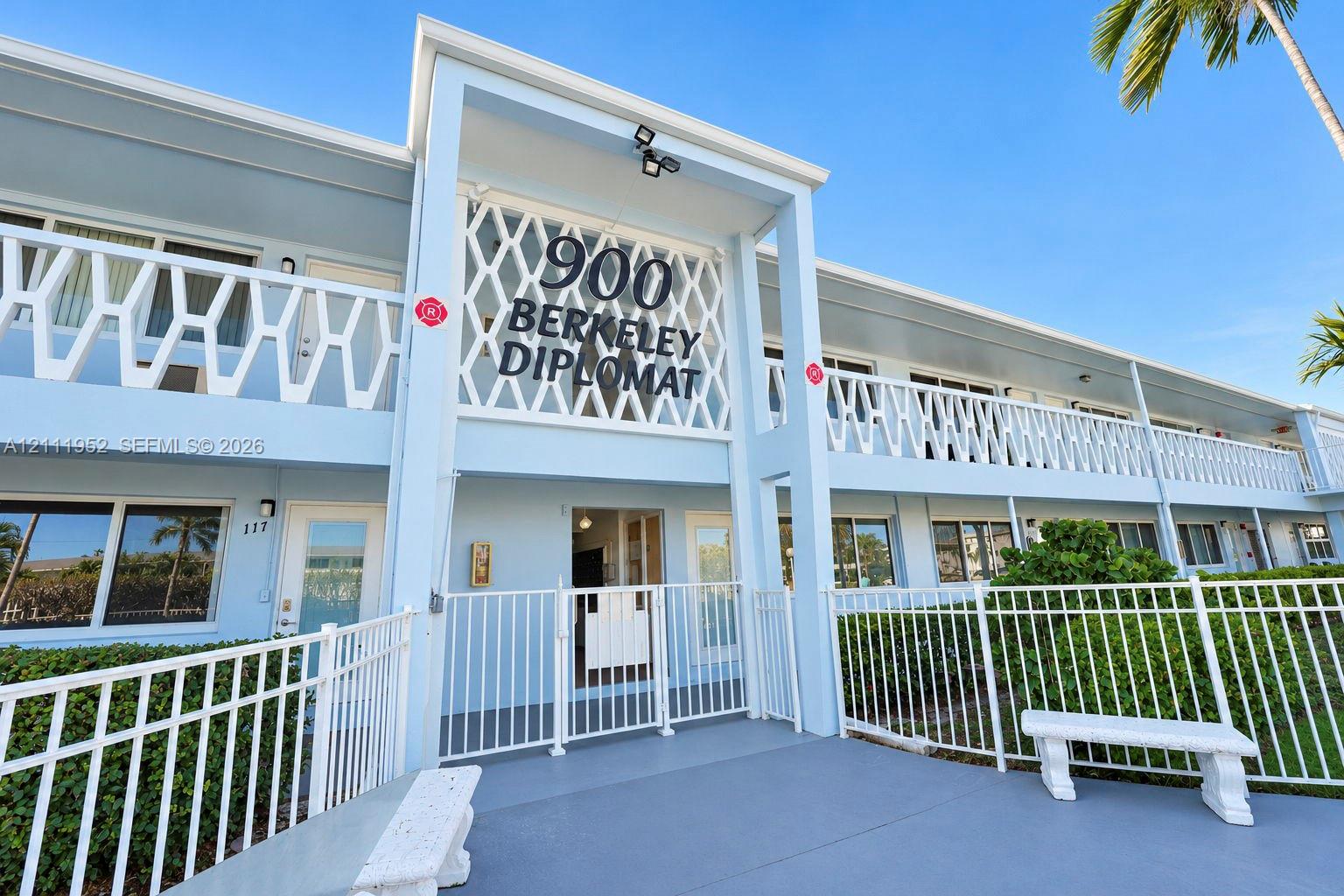 Mid-century architectural facade featuring a geometric latticework balcony railing, integrated covered entryway, and exterior building signage