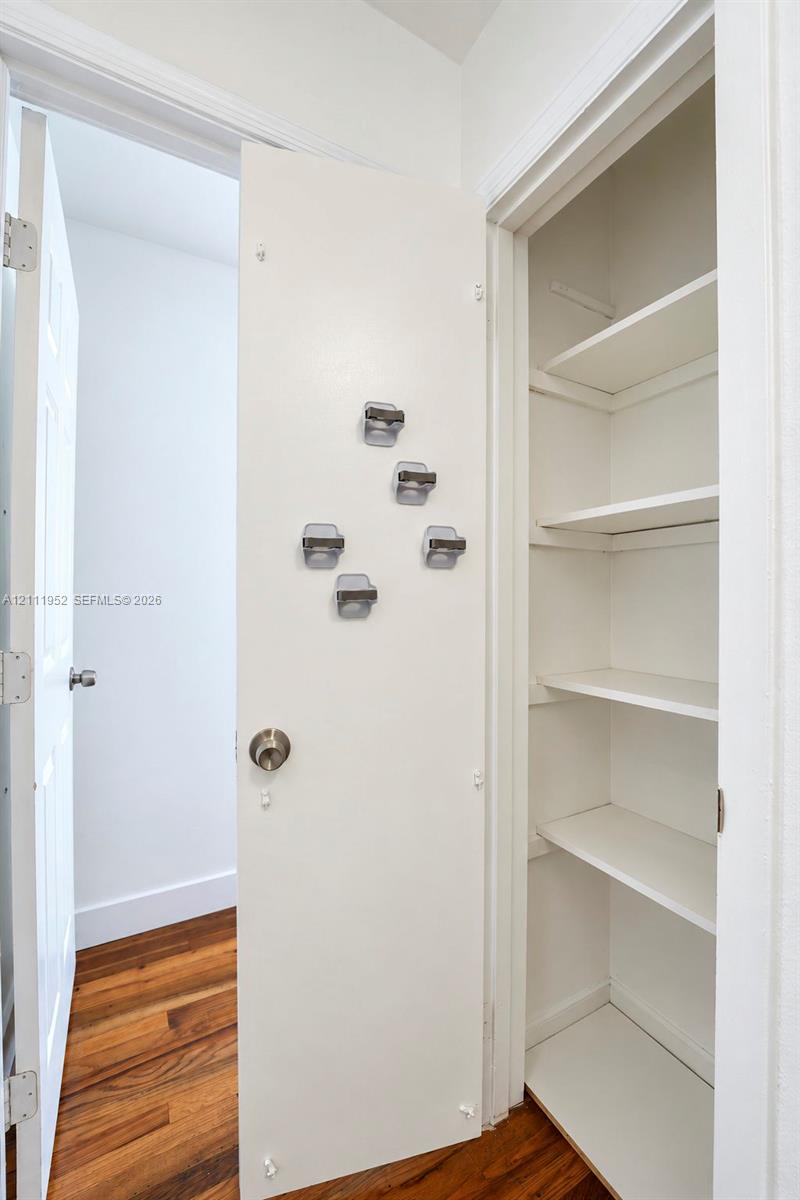 Built-in closet featuring multi-tiered shelving and wood-finish flooring