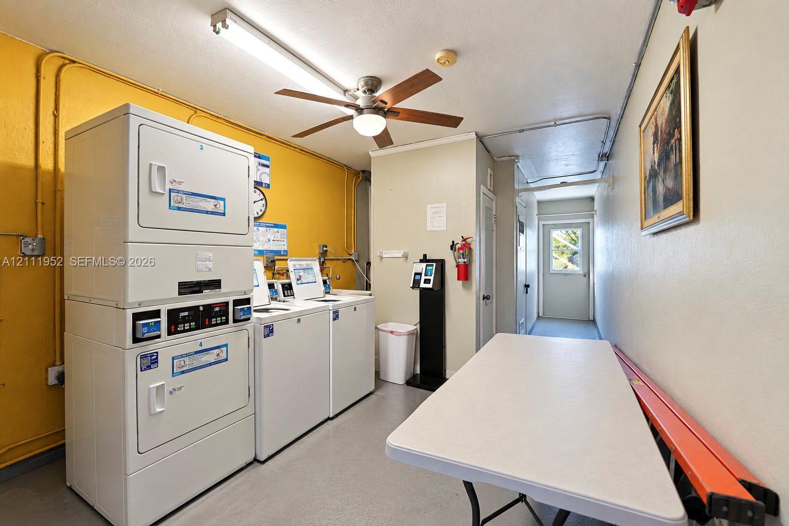 Laundry room featuring stacked washer-dryer units, side-by-side top-load washers, a ceiling fan with integrated lighting, and painted concrete flooring