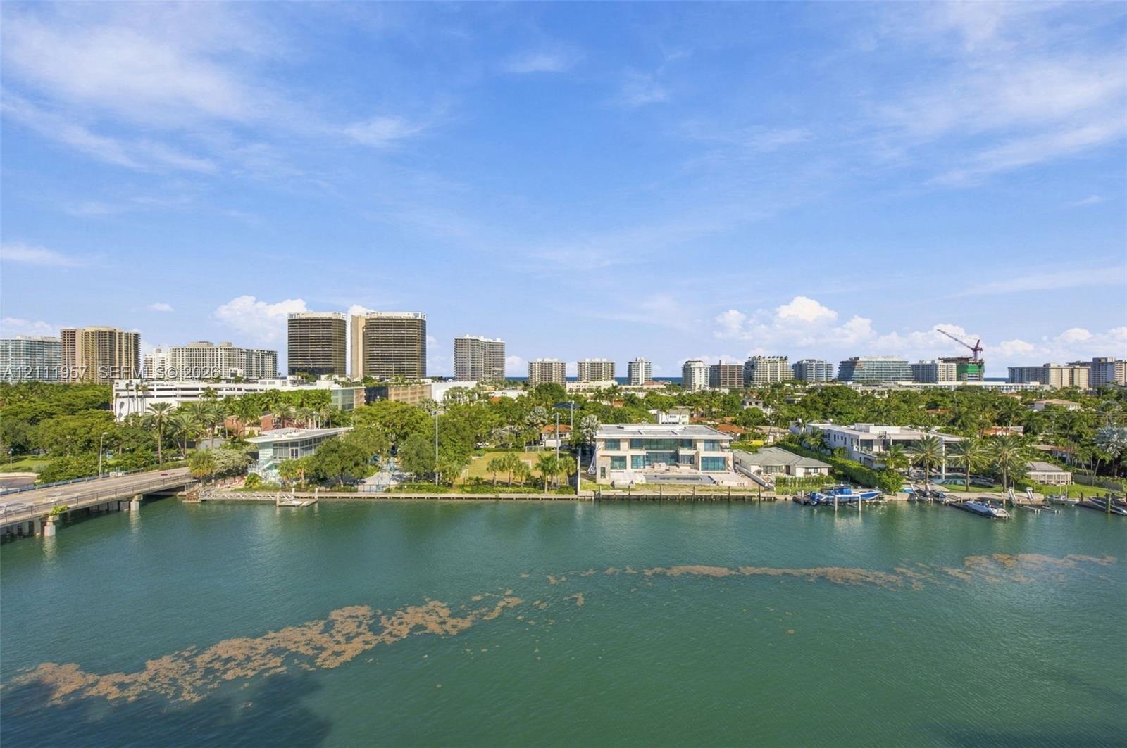 Waterfront estate featuring a paved pool deck, private dock, two-story structure with extensive glass glazing, and mature perimeter landscaping Waterfront estate featuring a paved pool deck, private dock, two-story structure with extensive glass glazing, and mature perimeter landscaping