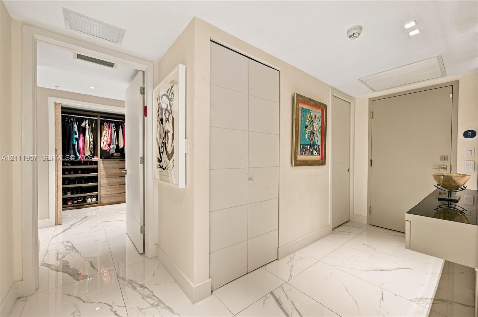 Large-format tile flooring, built-in floor-to-ceiling cabinetry with panel detailing, and custom walk-in closet featuring wood-finish shelving and drawer units