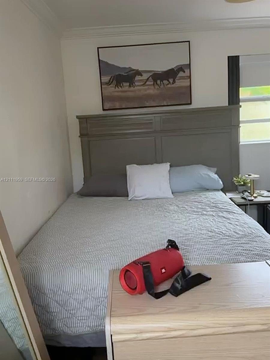 Neutral-toned interior space featuring crown molding and a window with a roller shade