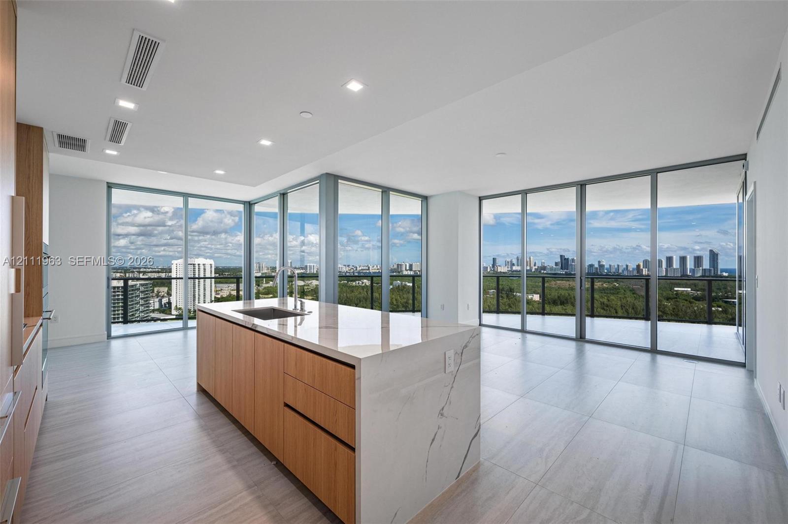Curved balcony featuring large-format tile flooring, a glass-panel railing, and full-height floor-to-ceiling sliding glass doors