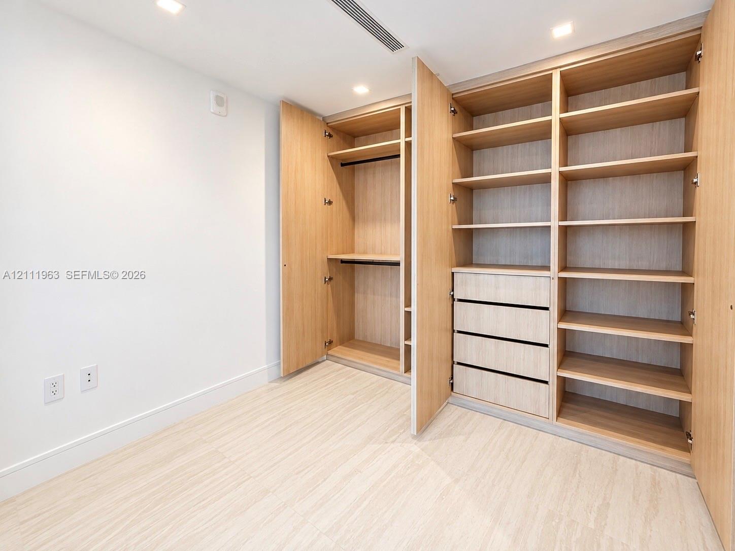Custom-built light wood-finish storage cabinetry featuring integrated shelving, four stacked drawers, and dual hanging rods