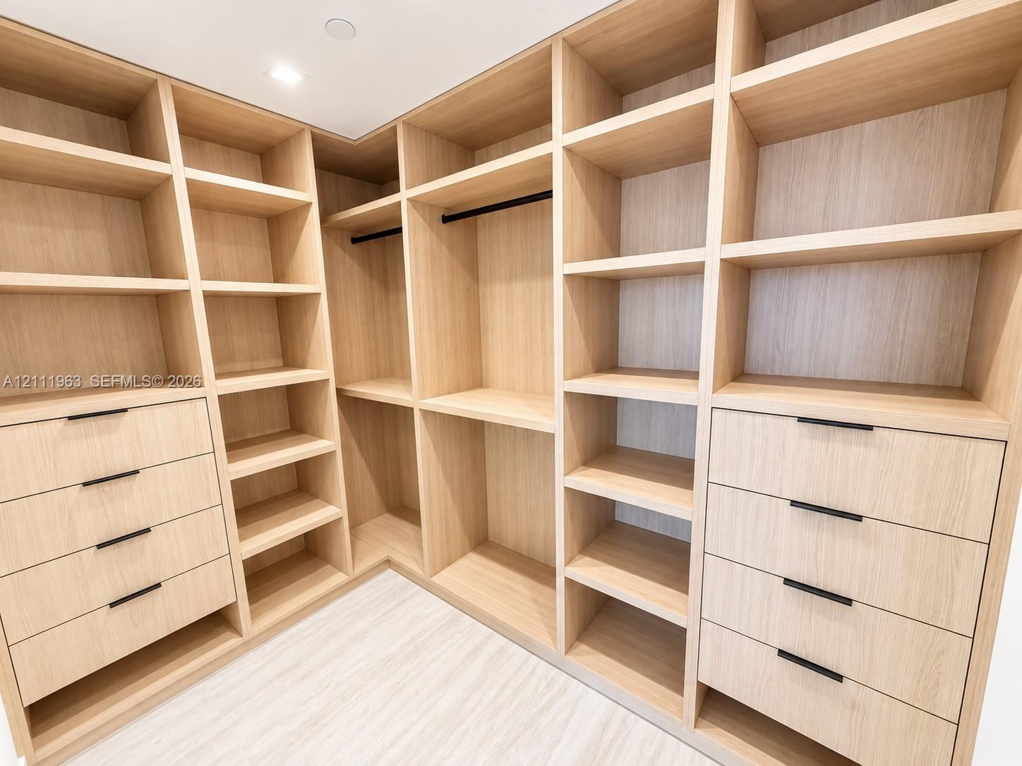 Interior space featuring light-toned wood-finish flooring, recessed ceiling lighting, and floor-to-ceiling built-in wooden cabinetry