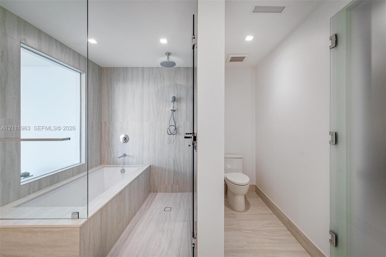 Dual-sink vanity featuring a light-toned countertop, wood-finish cabinetry, integrated rectangular basins, wall-mounted faucets, and an expansive mirror with integrated vertical lighting