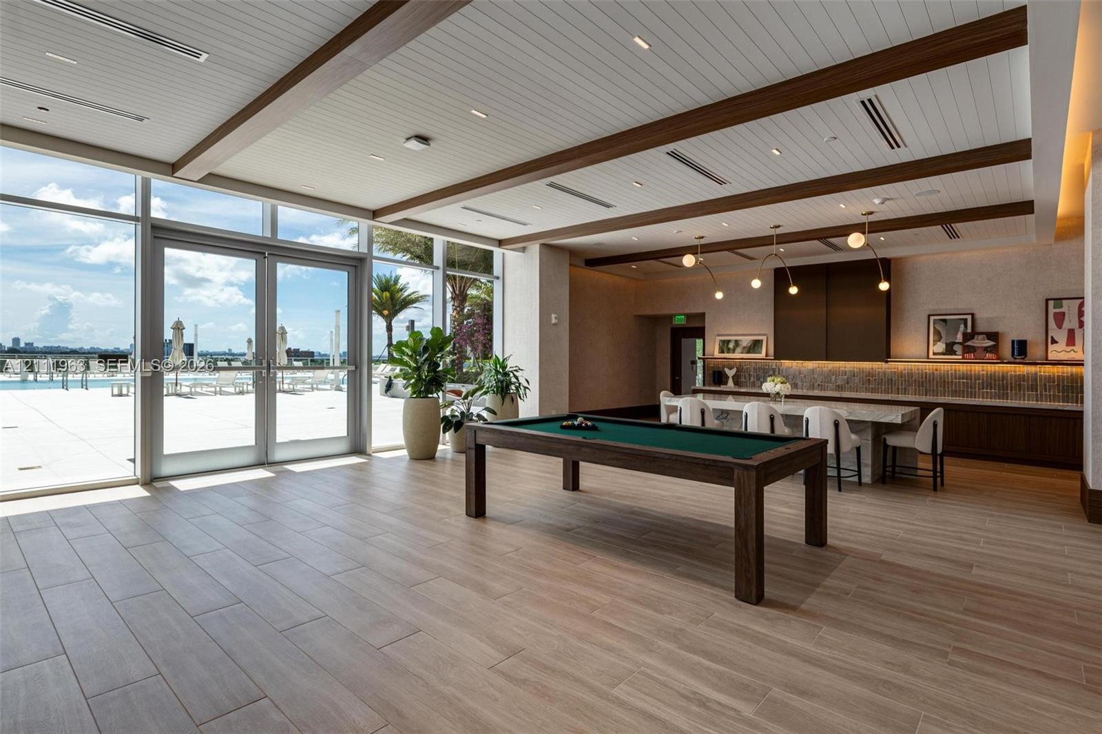 Fitness center featuring floor-to-ceiling windows, wood-finish flooring, custom recessed ceiling lighting, and motorized roller shades