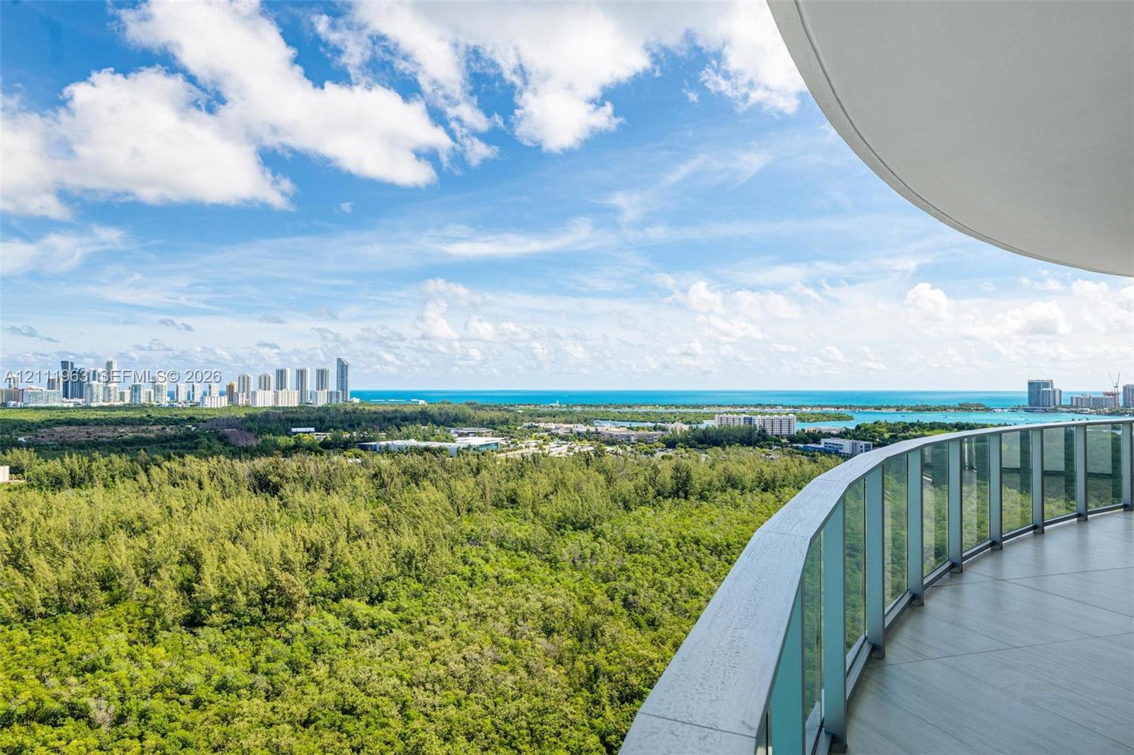 Aerial perspective featuring a large turquoise lagoon, sandy shoreline, manicured green space, and surrounding urban landscape