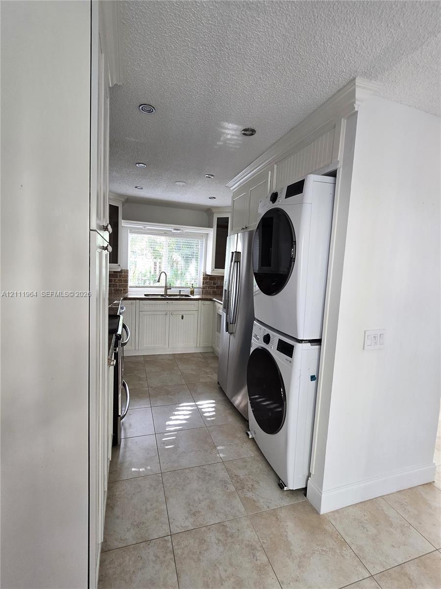 Kitchen featuring white beadboard cabinetry, recessed ceiling lighting, tile flooring, and integrated laundry appliances