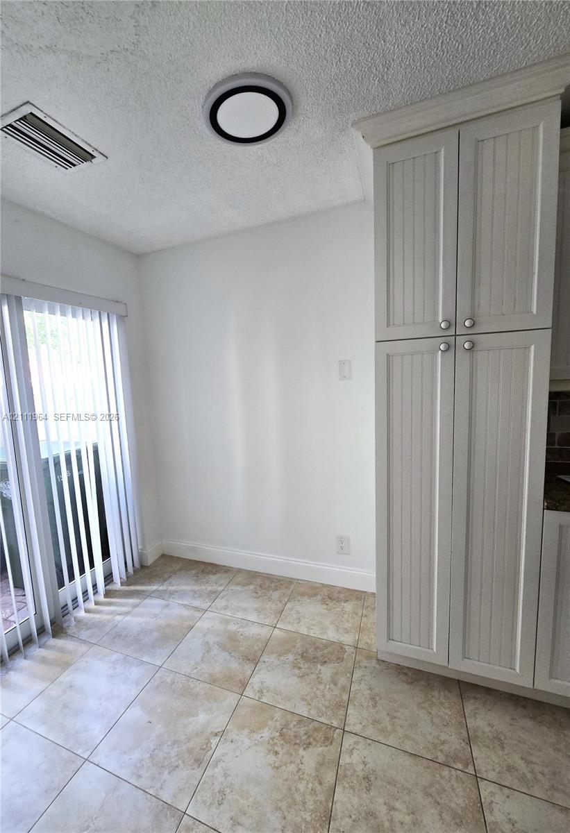 Tall white beadboard-style cabinetry, square stone-finish floor tiling, and a recessed ceiling light fixture