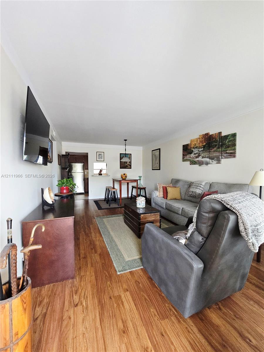 Open-concept interior featuring wood-finish flooring, a wall-mounted television, neutral paint, and an overhead pendant light fixture