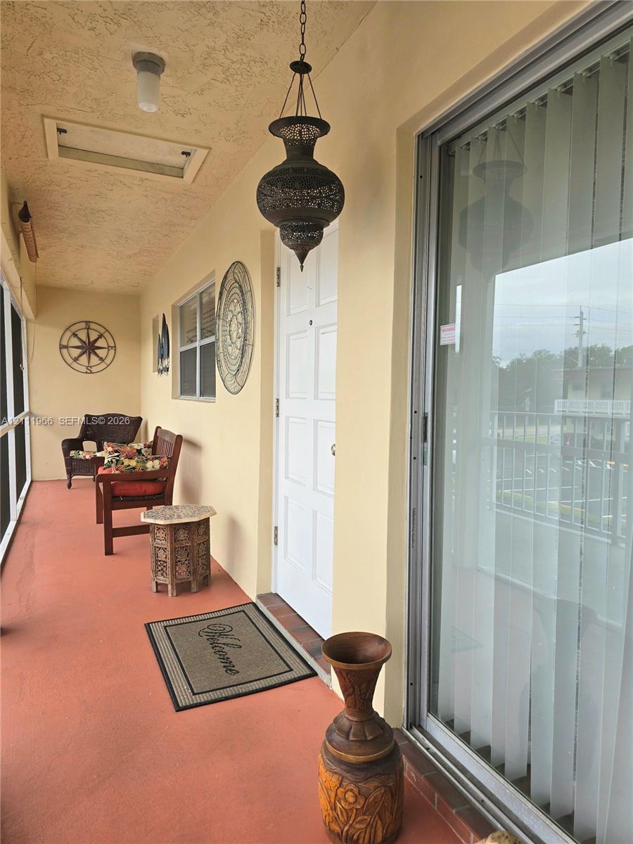 Covered outdoor patio featuring a textured ceiling, ornamental pendant lighting, and full-height sliding glass doors Covered outdoor patio featuring a textured ceiling, ornamental pendant lighting, and full-height sliding glass doors