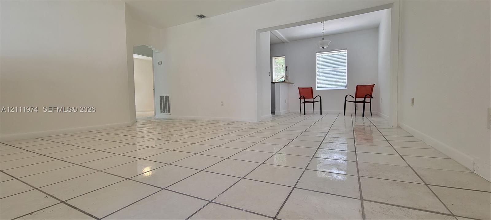 Interior space featuring white tile flooring, neutral wall paint, and an overhead pendant light fixture