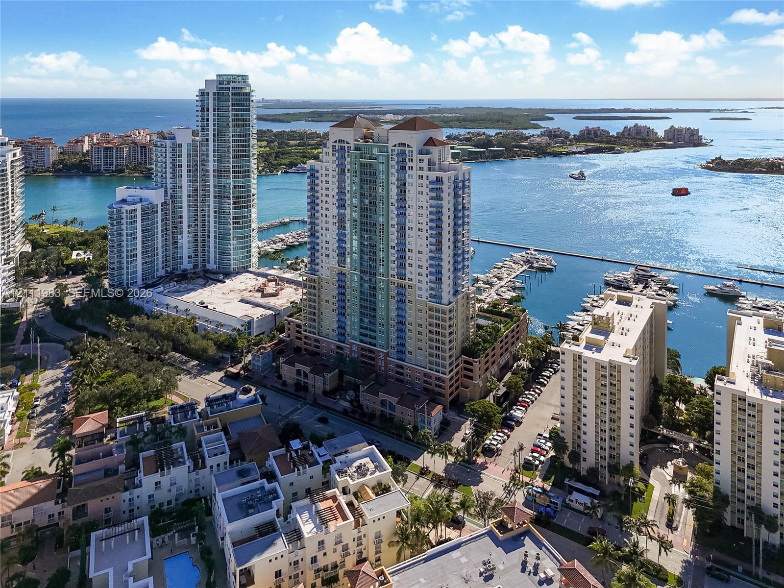 High-rise residential tower featuring a multi-story glass and concrete facade, situated on a waterfront lot with deep-water boat slips and a peripheral parking structure