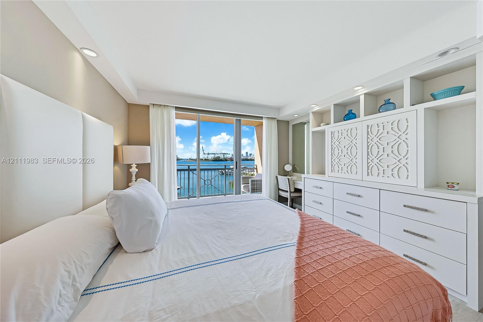 Built-in wall-to-wall cabinetry with integrated open shelving and drawers, floor-to-ceiling glass sliding doors, recessed lighting, and water scenery