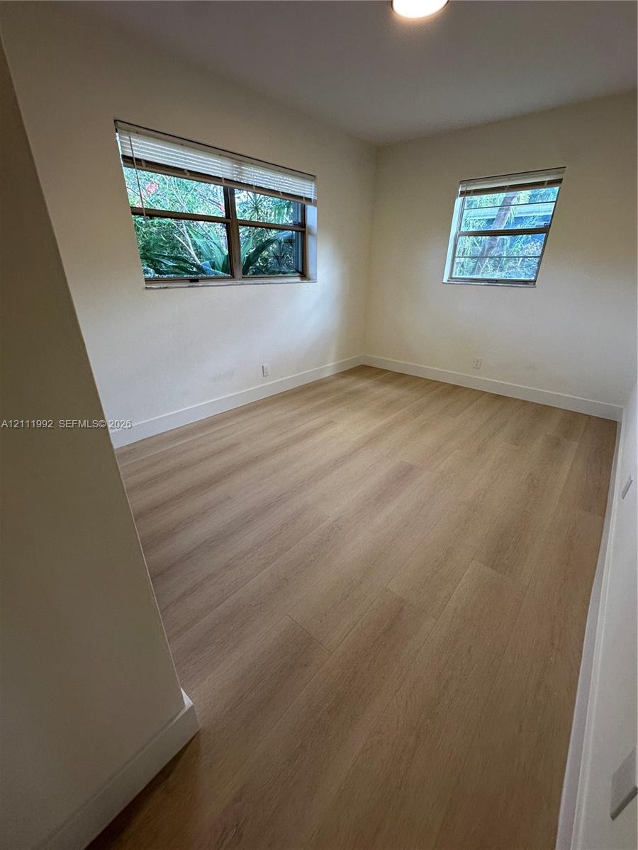 Neutral wall tones, wood-finish flooring, and multiple windows with integrated blinds