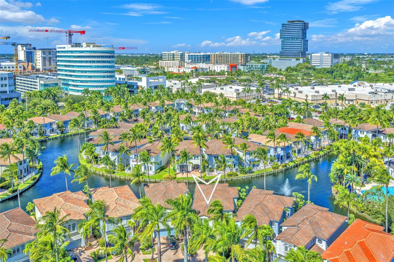 Aerial perspective of a multi-story residential structure featuring a tiled roof, positioned on a waterfront lot with canal access and surrounding tropical landscaping