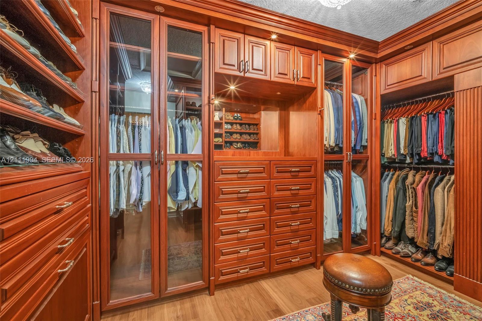 Custom wood cabinetry featuring glass-front doors, built-in shelving, integrated drawers, and recessed lighting