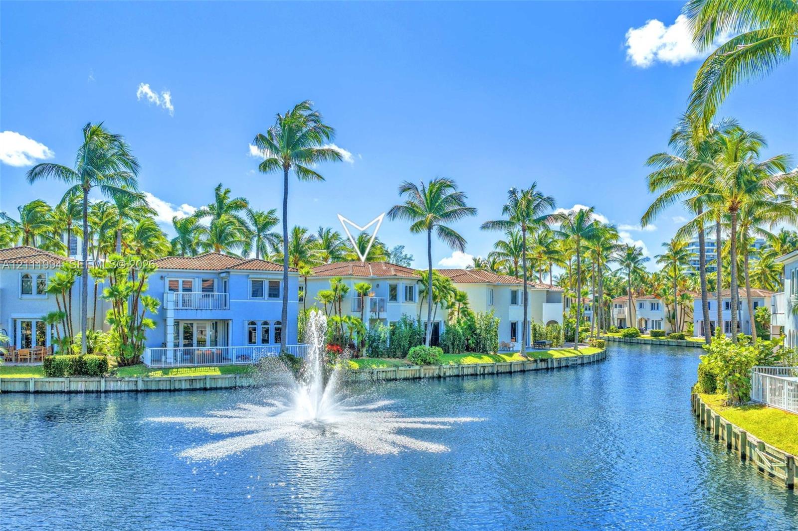 Waterfront exterior featuring a tile roof, stucco facade, private balconies, and a central water fountain