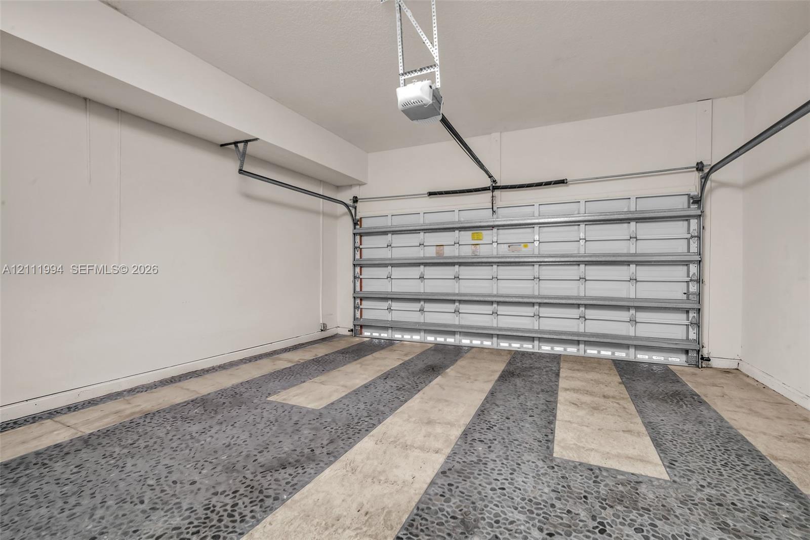 Garage featuring smooth-finish walls, a steel sectional door, and decorative aggregate concrete flooring