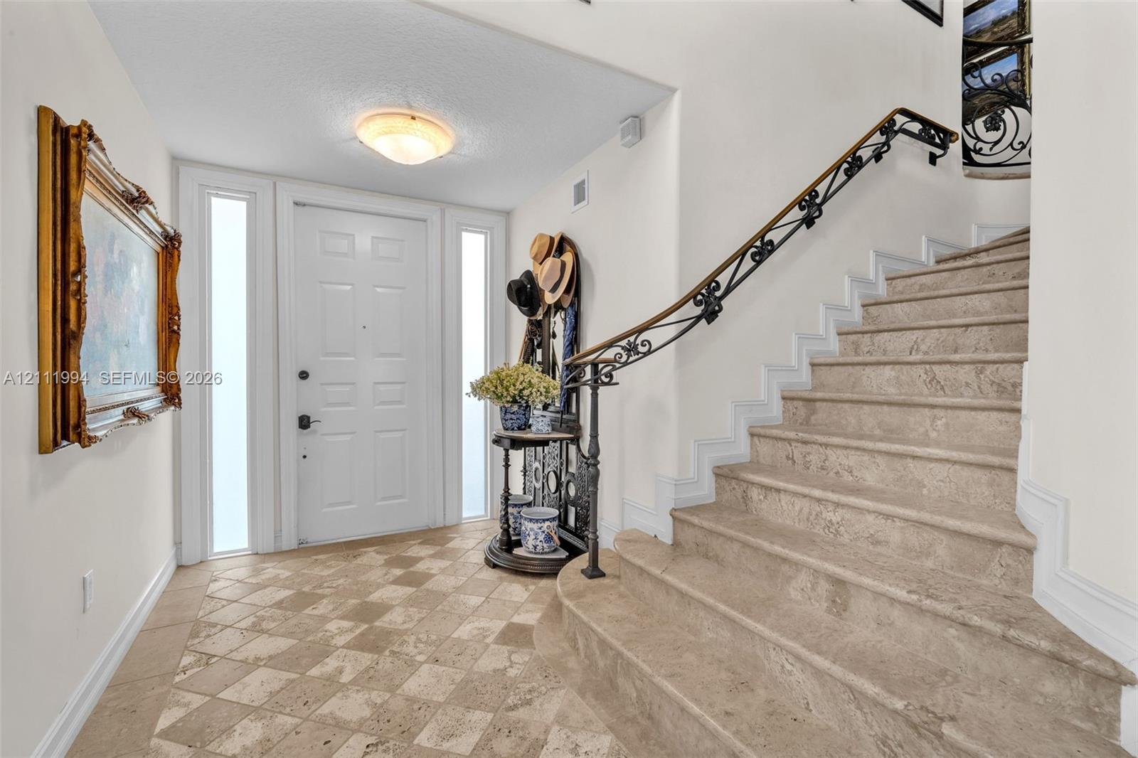 Entryway featuring stone tile flooring, a paneled door with dual sidelights, a custom iron handrail, and stone stairs