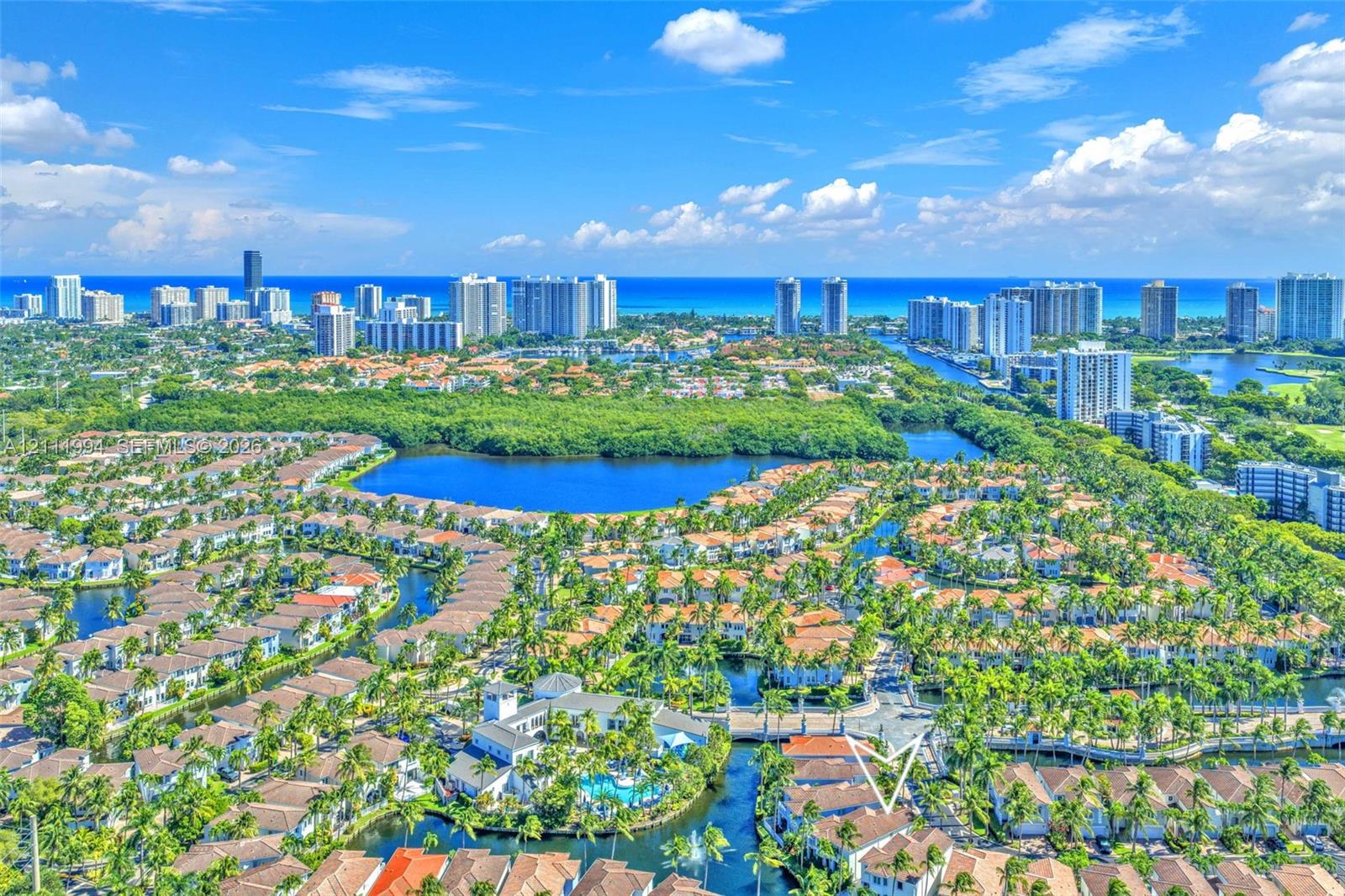 Aerial perspective featuring expansive water features, mature tropical landscaping, and proximity to the coastline