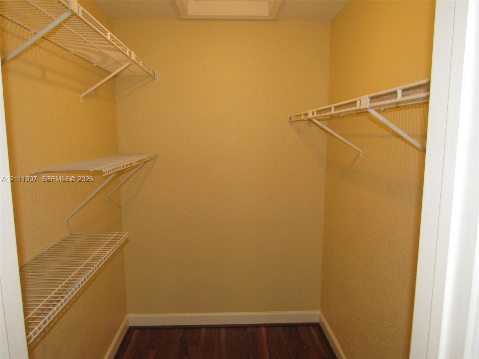 Storage area featuring white wire shelving units and wood-finish flooring