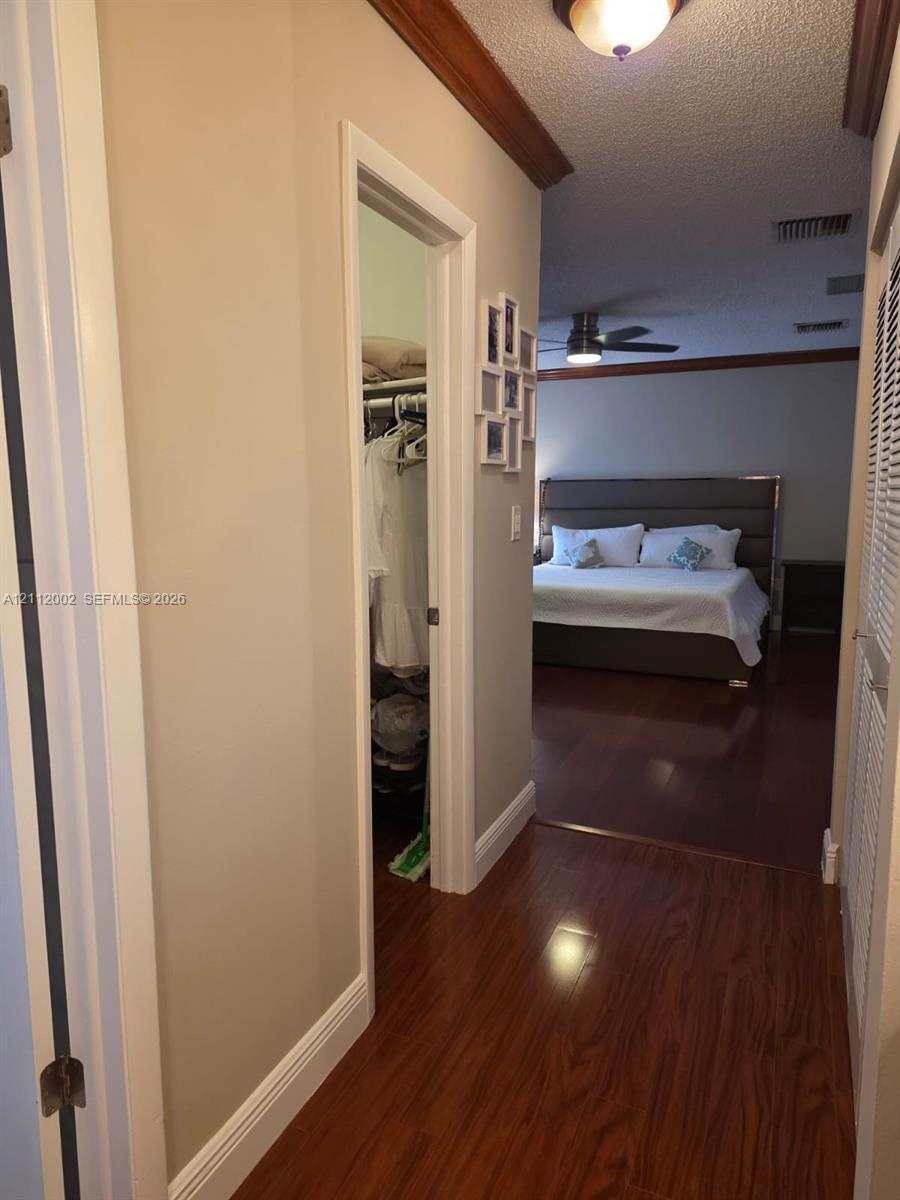 Wood-finish flooring, crown molding, and a louvered closet door