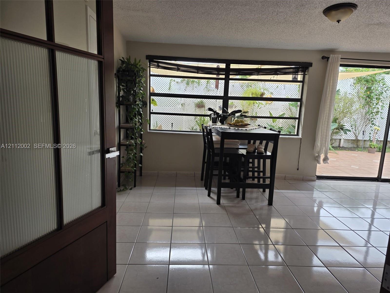 Interior space featuring large-format ceramic tile flooring, horizontal multi-pane windows, and a sliding glass door providing external access