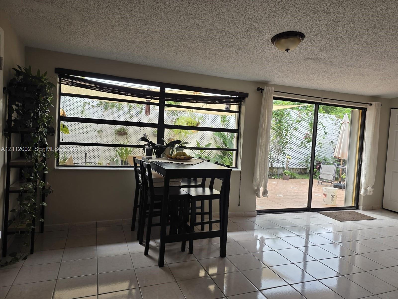 Large horizontal window with black frames, tile flooring, and sliding glass door