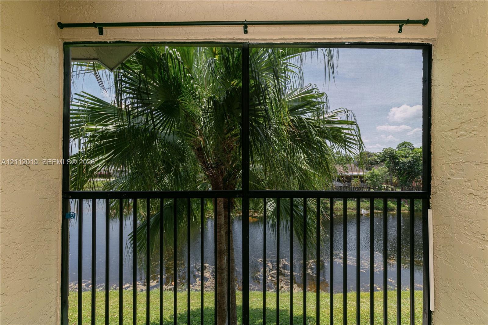 Screened-in enclosure featuring a black metal frame, textured wall finishes, and a curtain rod