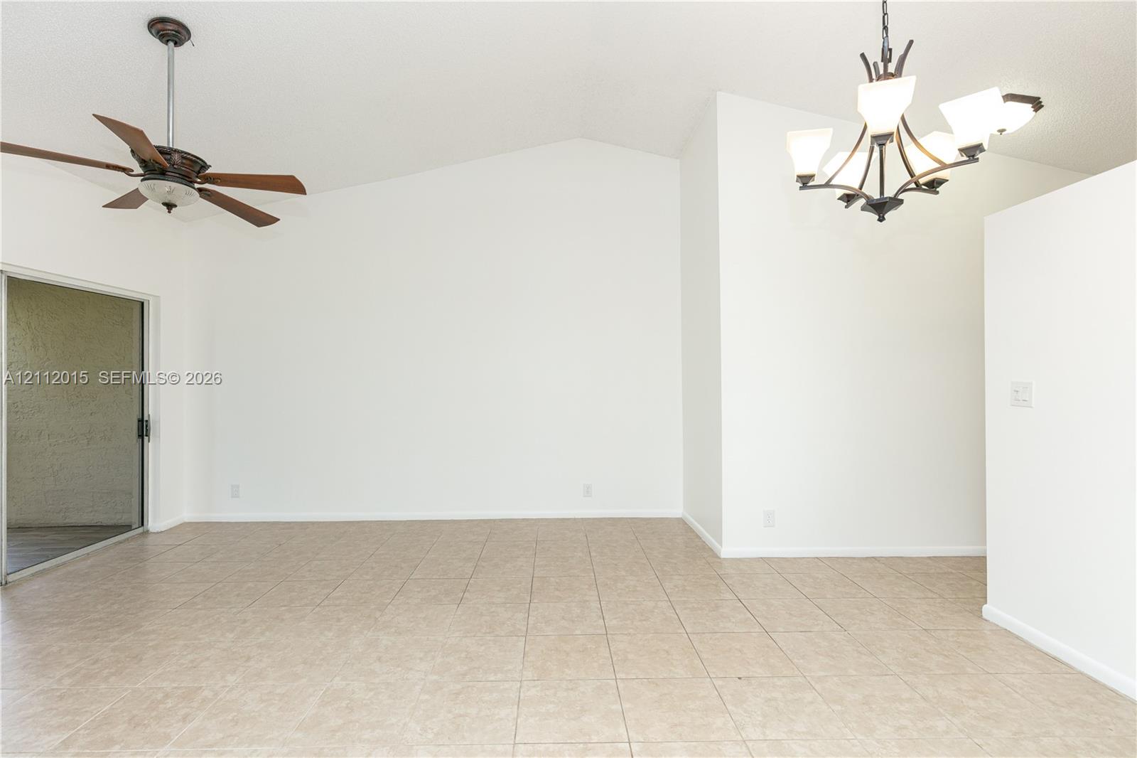 Vaulted ceiling, ceramic tile flooring, multi-arm metal chandelier, ceiling fan with wood-finish blades, and sliding glass door