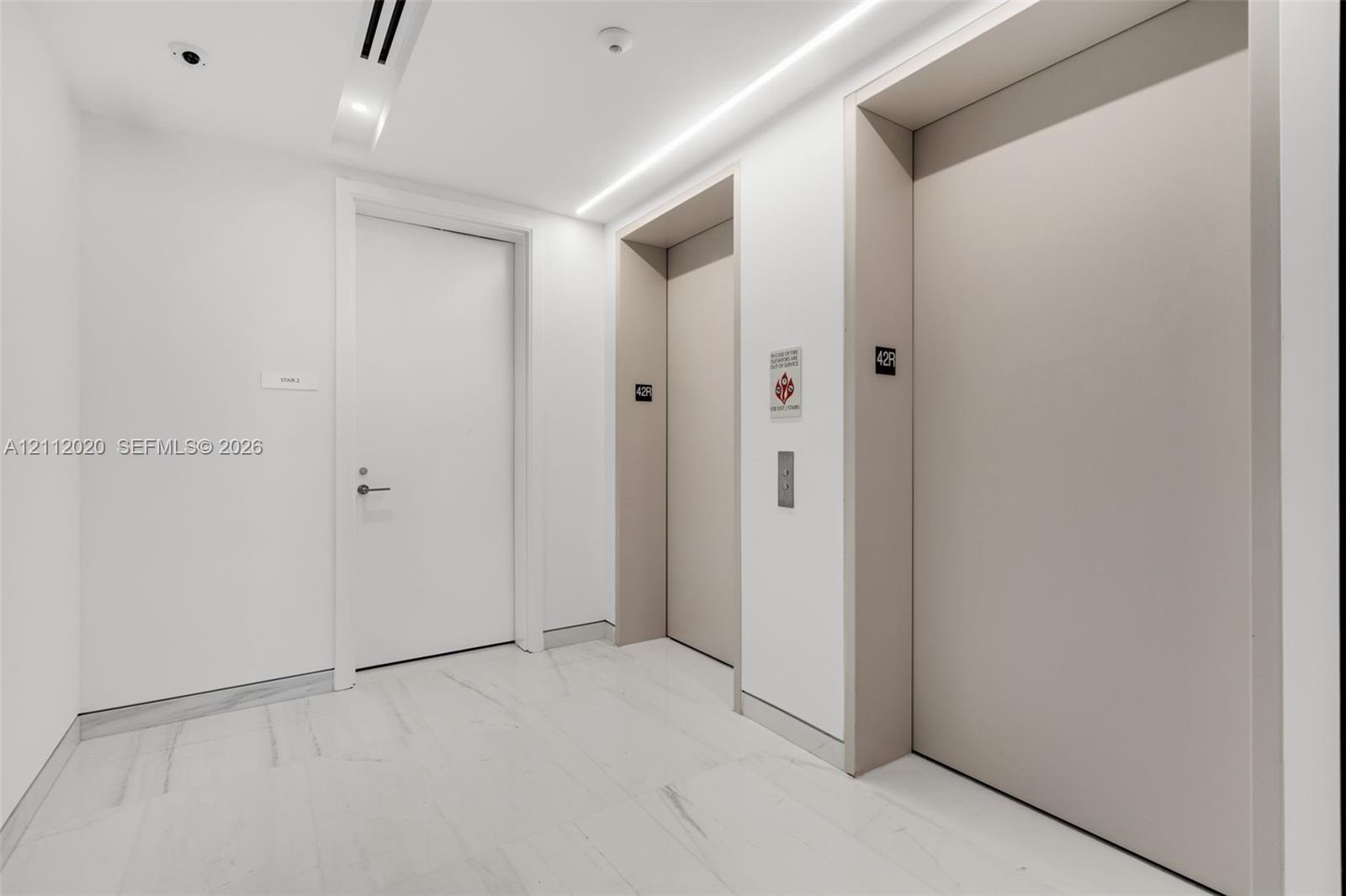 Elevator lobby featuring stone-finish flooring, recessed linear ceiling lighting, and clean, minimalist wall finishes Elevator lobby featuring stone-finish flooring, recessed linear ceiling lighting, and clean, minimalist wall finishes
