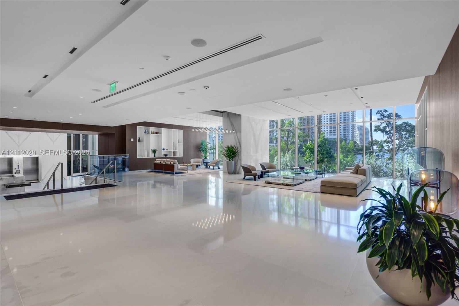 Spacious lobby featuring polished stone flooring, floor-to-ceiling windows, recessed architectural ceiling lighting, and built-in wall niches