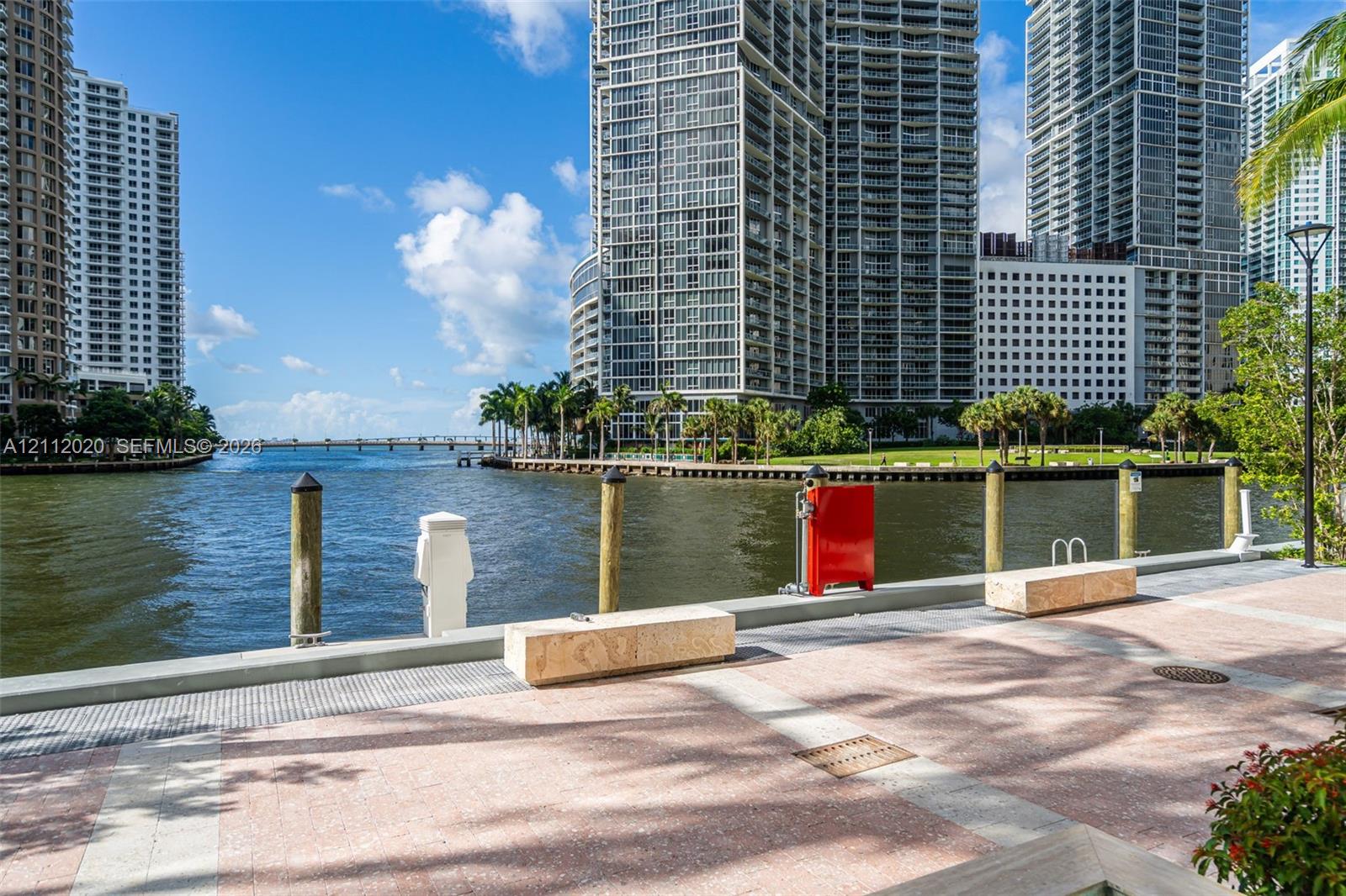 Waterfront promenade featuring stone paver walkways, integrated stone seating, timber piling bulkheads, and metal light fixtures