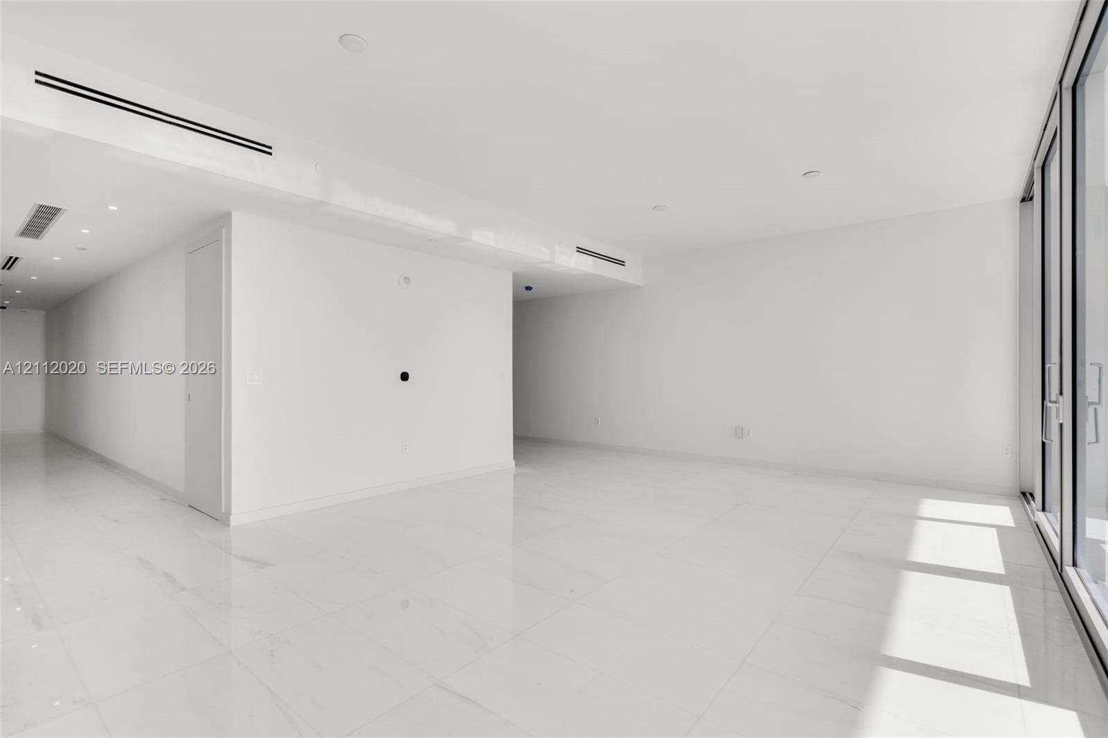 Interior space featuring large-format tile flooring, recessed ceiling lighting, and floor-to-ceiling glass paneling