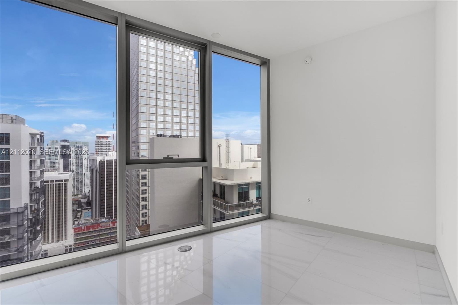 Floor-to-ceiling windows with expansive urban cityscape, polished light-toned tile flooring, and metallic-finish window frames