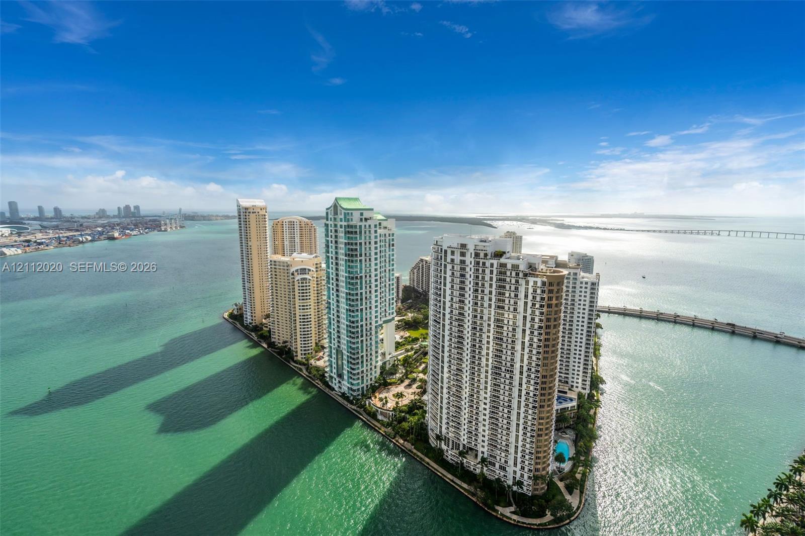 Aerial perspective of a high-rise residential complex located on a waterfront peninsula, featuring direct coastal access, multi-story architecture, and surrounding marine environment